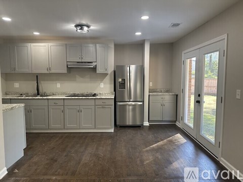 A kitchen with white cabinets and a stainless steel refrigerator.