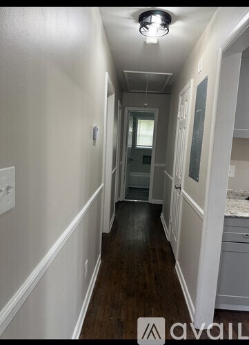A long hallway with white walls and wood floors.