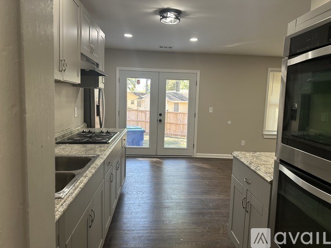 A kitchen with a view of a backyard through the sliding glass doors.