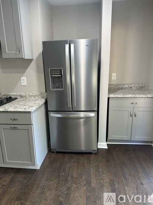 A stainless steel refrigerator in a kitchen with white cabinets.