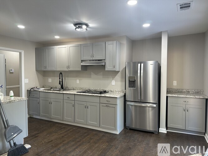 A kitchen with a refrigerator, sink, and cabinets.