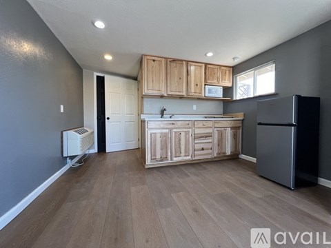 A kitchen with wooden cabinets and a black refrigerator.