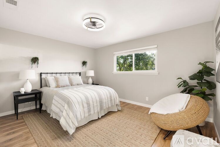 A well-lit bedroom with a large bed and a chair.