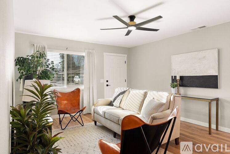 A living room with a white couch, a brown chair, and a ceiling fan.
