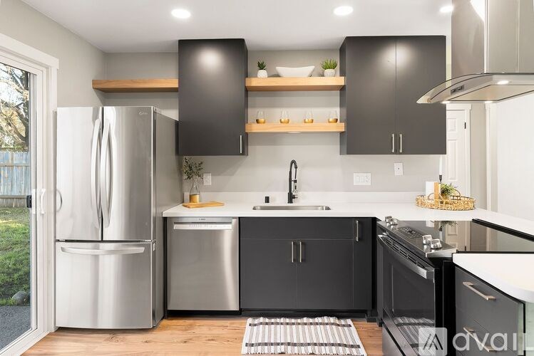 A modern kitchen with black cabinets and stainless steel appliances.