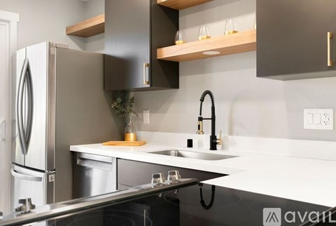 A kitchen with a white counter top and a black fridge.