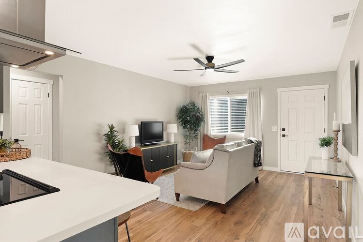 A living room with a couch, a television, and a ceiling fan.