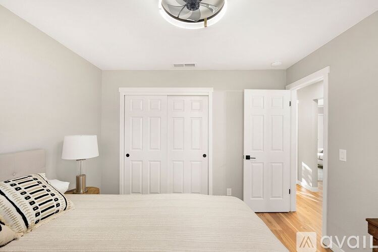 A bedroom with a bed, lamp, and two doors.