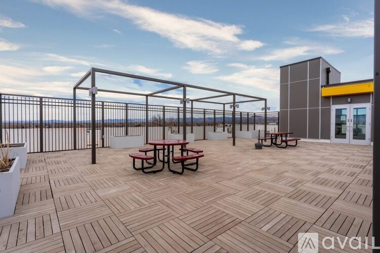 A wooden deck with picnic tables and a metal railing.
