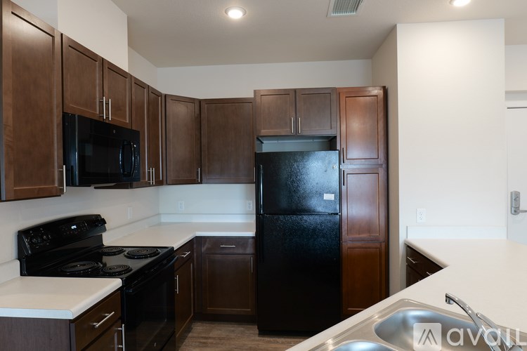 A kitchen with brown cabinets and black appliances.