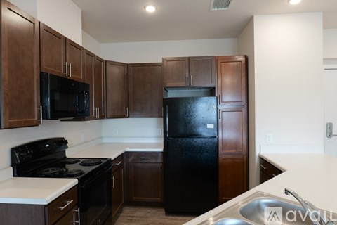 A kitchen with brown cabinets and black appliances.