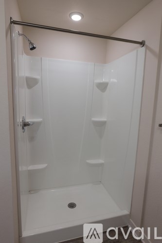 A white shower stall with a glass door and a shower head.