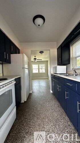 A kitchen with a white stove top oven and black cabinets.