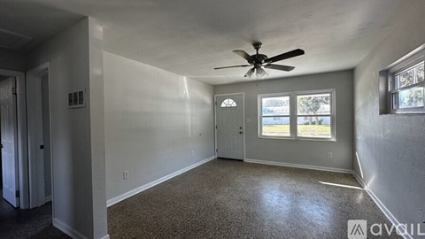 A spacious room with a ceiling fan and carpeted floor.