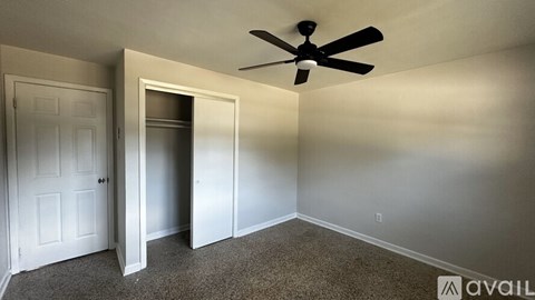 A room with a ceiling fan and a doorway leading to another room.