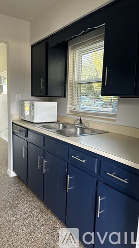 A kitchen with black cabinets and a white microwave.