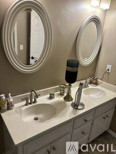 A bathroom with a sink, mirror, and a round mirror above it.