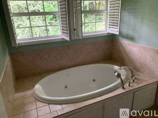 A bathroom with a tub and a window with shutters.