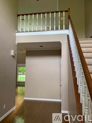 A staircase with a wooden handrail and white balusters leads to a landing with a doorway.