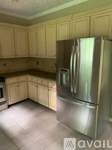 A kitchen with a stainless steel refrigerator and wooden cabinets.