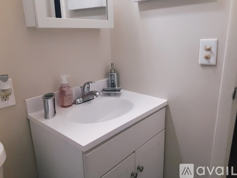 A white bathroom sink with a silver faucet and a pink soap dispenser.