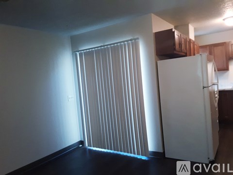 A room with a white wall and a white refrigerator.