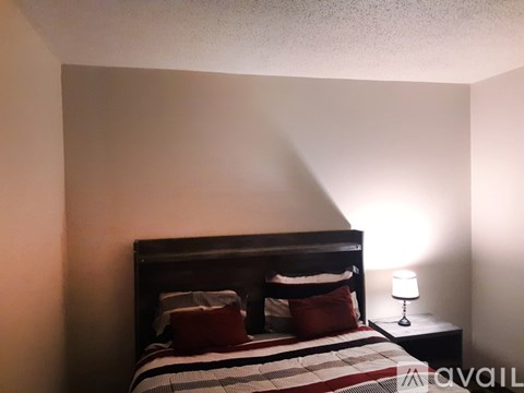 A bedroom with a bed, pillows, and a lamp.