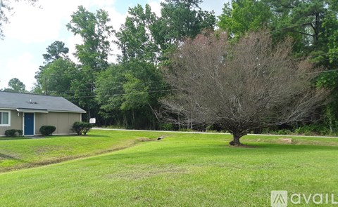 A house with a blue door is surrounded by a grassy area and trees.
