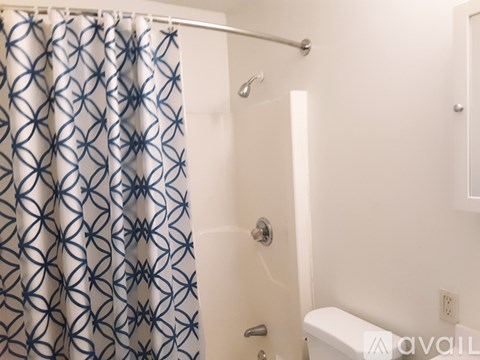 A shower curtain with a blue pattern hangs over a white bathtub.