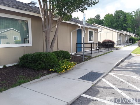 A tree is in front of a house and apartment buildings.