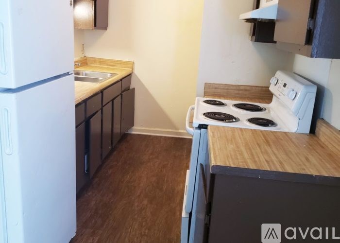 A kitchen with a white fridge, sink, and stove.