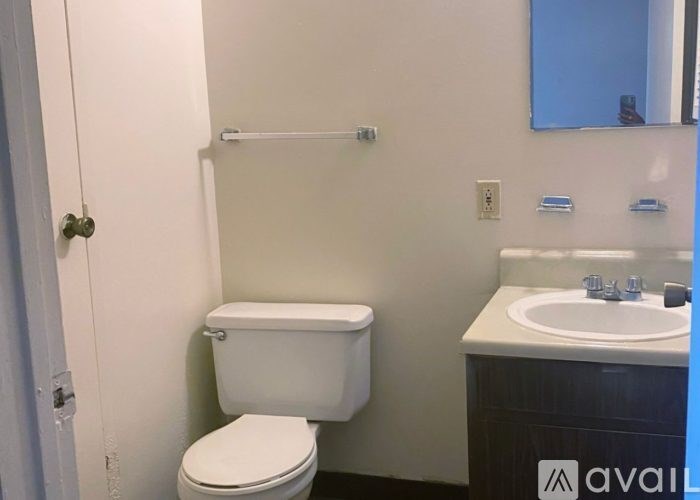A white toilet is in a small bathroom with a white sink.
