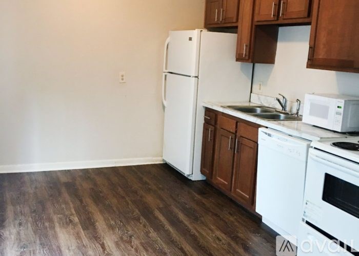 A kitchen with white appliances and wooden cabinets.