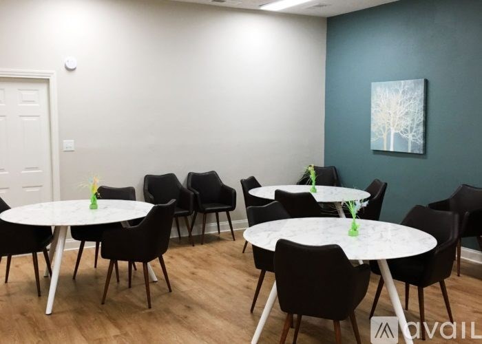 A room with white tables and black chairs.