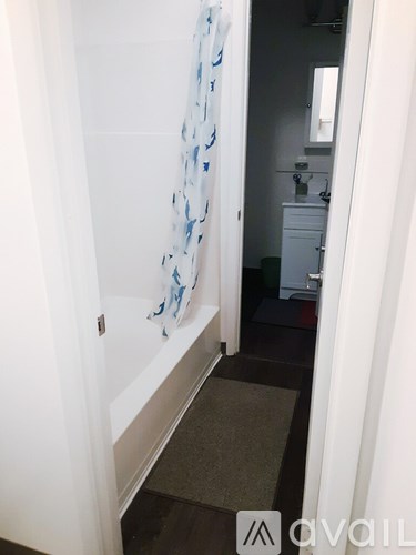 A bathroom with a white door and a blue and white shower curtain.
