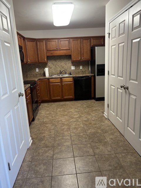 A kitchen with brown cabinets and a black fridge.