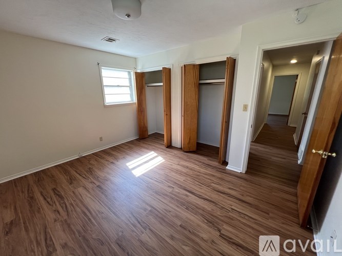 A room with wooden flooring and a window letting in sunlight.