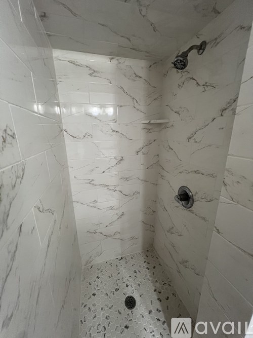A shower area with a marble tile wall and floor.