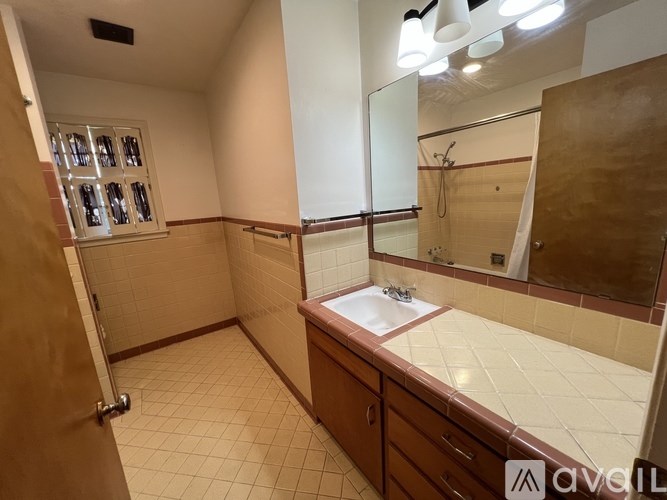 A bathroom with a sink, mirror, and tiled walls.