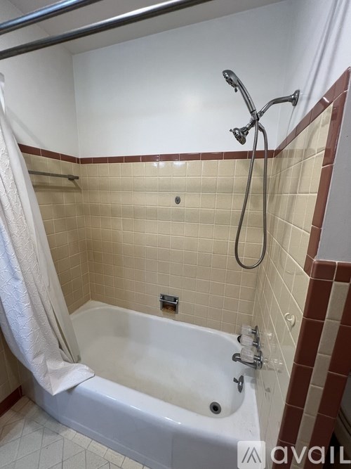 A white bathtub with a shower head and a white towel hanging on the side.