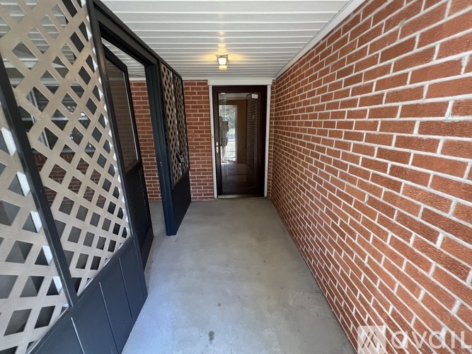 A hallway with a brick wall and a doorway.