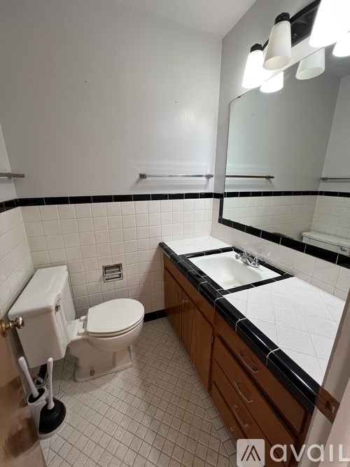 A bathroom with a toilet, sink, and mirror.