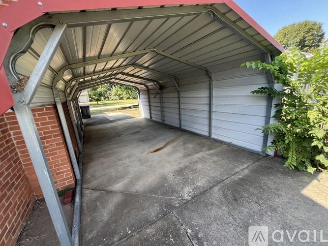 A covered parking area with a concrete floor and a brick column.