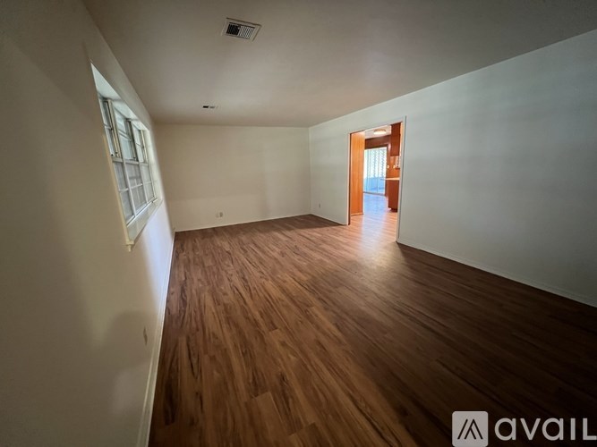 A room with wooden flooring and a doorway leading to another room.
