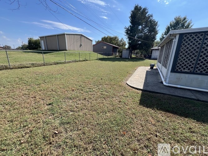 A grassy field with a fence and a building in the background.