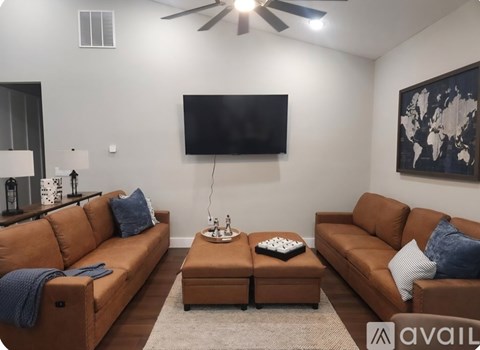 A living room with a brown sofa and a flat screen TV mounted on the wall.