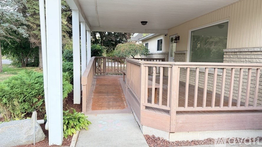 A porch with a wooden railing and a concrete floor.