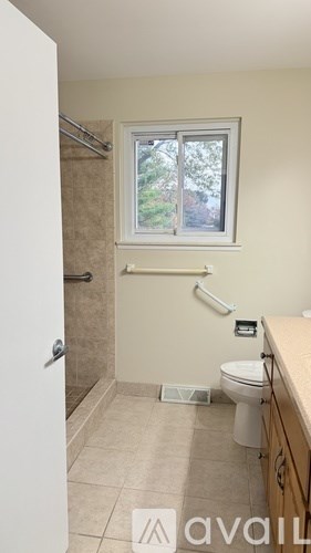 A bathroom with a toilet, sink, and window.
