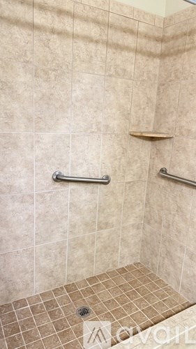 A tiled shower with a drain in the middle.