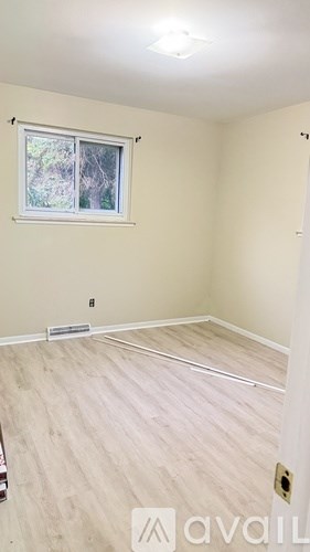 A room with a window and wooden flooring.